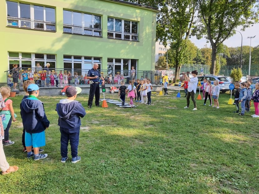 policjant ruchu drogowego uczący przechodzić dzieci przez pasy