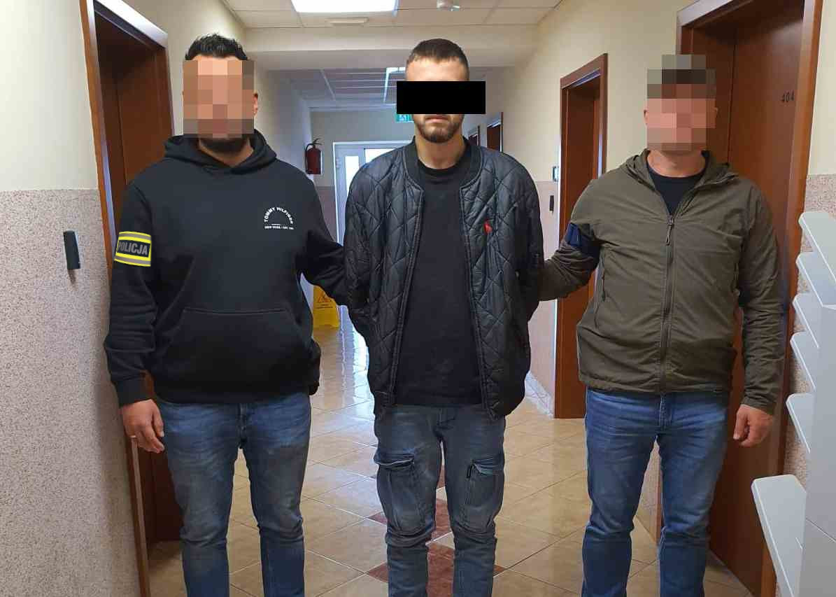 Policjanci prowadza zatrzymanego mężczyznę.