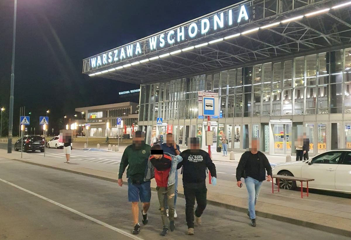 Policjanci wyprowadzają zatrzymanego mężczyznę z dworca Warszawa Wschodnia.