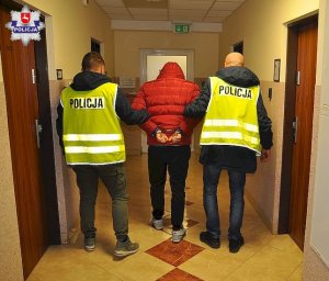 skuty kajdankami  mężczyzna doprowadzany przez dwóch policjantów