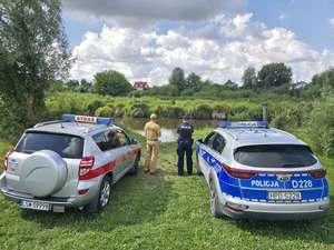 strażacy i policjanci kontrolujący teren nadrzeczny