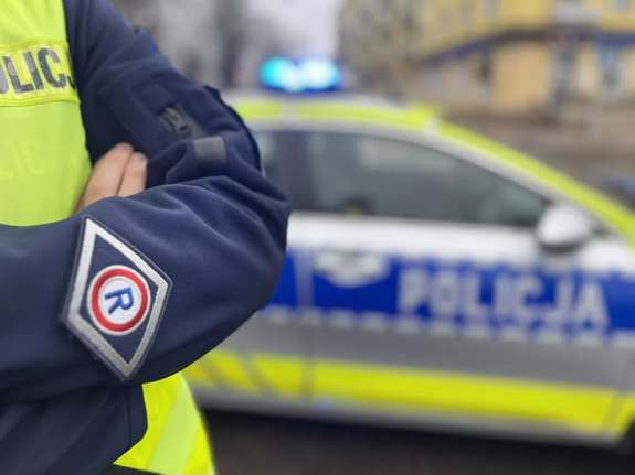 zdjęcie przestawiające policjanta ruchu drogowego przy radiowozie